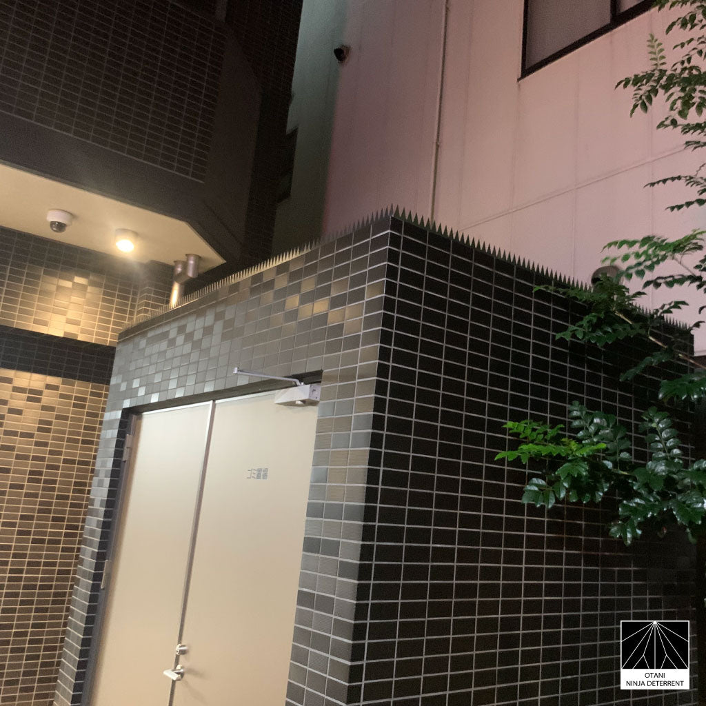 Nighttime view of GIZAGIZA Stainless installed on tiled exterior – sleek urban protection