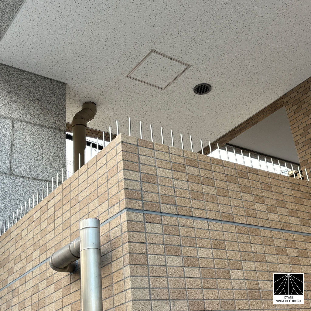 Sleek silver Ninja Deterrent™ installed on modern brick wall—discreet bird and intruder deterrent